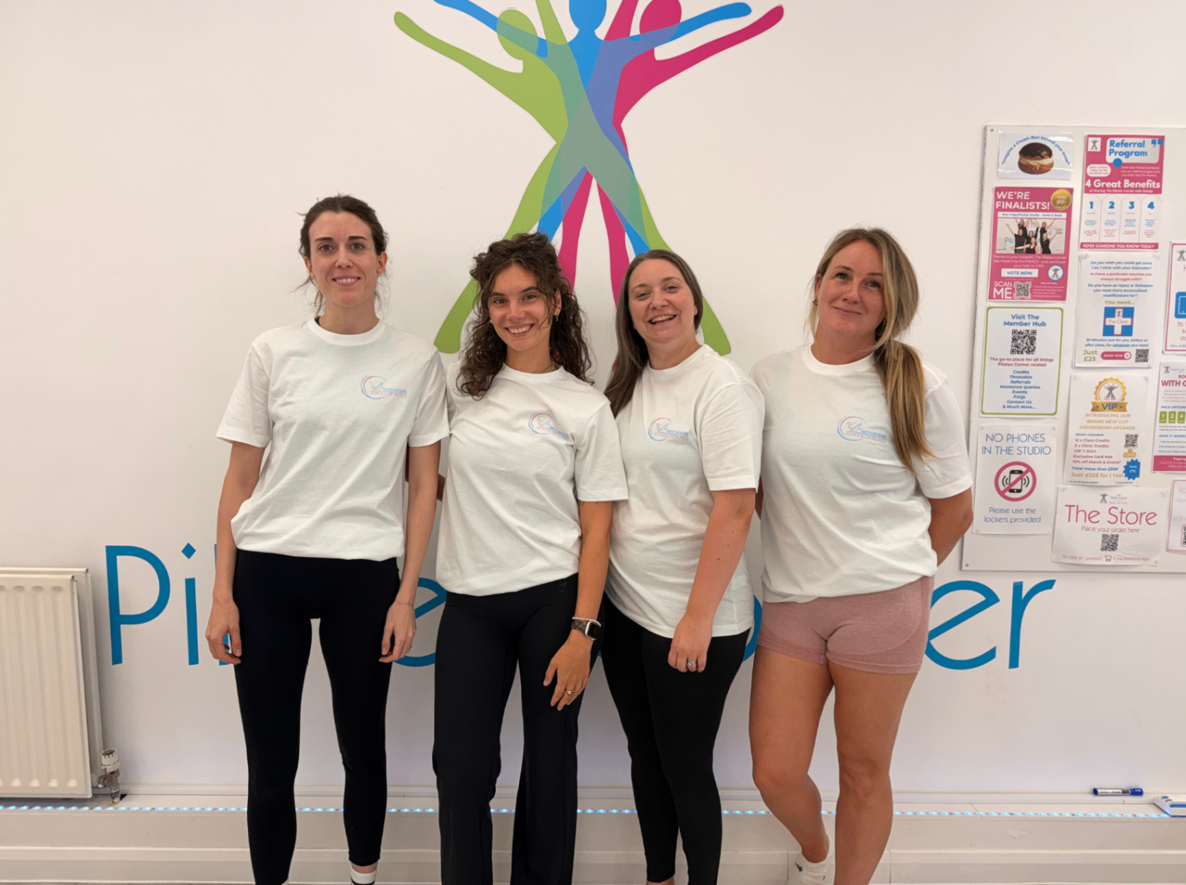 Four HSP students in white t-shirts standing in front of the HSP branding wall